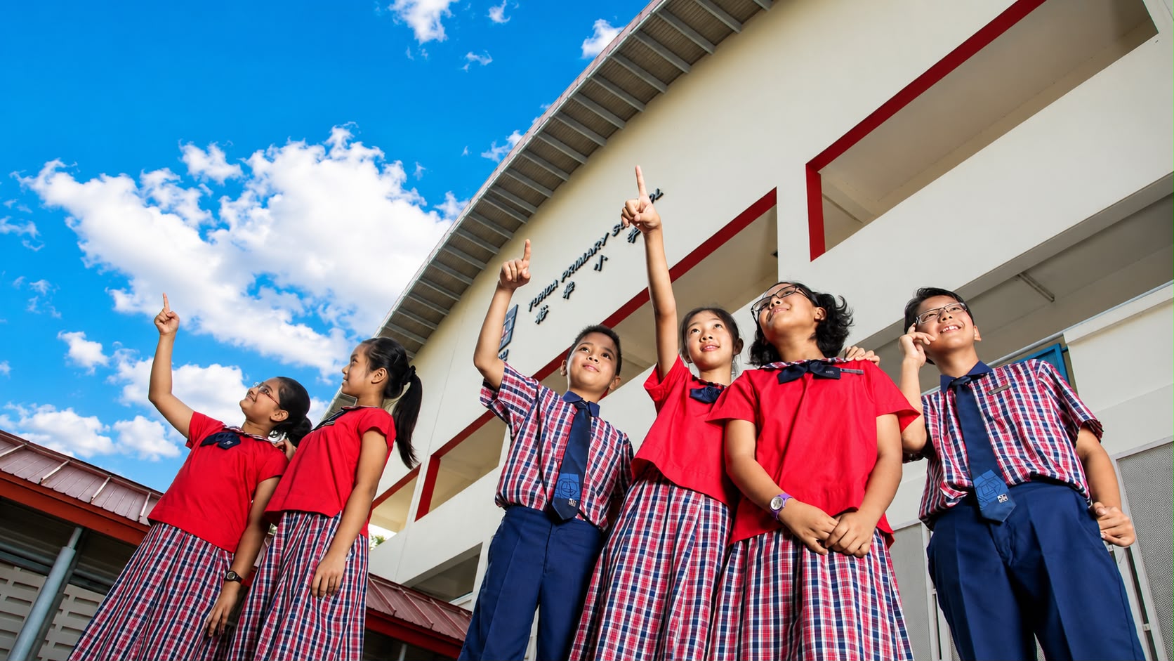 Yuhua Primary pupils wearing red blouses with checked skirts and checked shirts with blue shorts